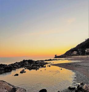 a sunset over a beach with rocks in the water at Living Piraino casa vacanze in Piraino