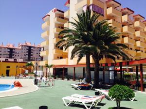 a resort with a pool and palm trees and chairs at CARLETTO Los Angeles Los Cristianos in Los Cristianos