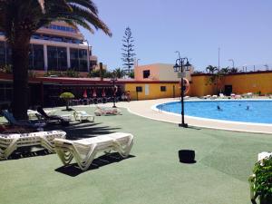 a pool with chaise lounge chairs and a resort at CARLETTO Los Angeles Los Cristianos in Los Cristianos