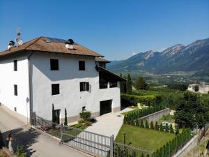 une maison blanche avec une clôture et des montagnes en arrière-plan dans l'établissement Al Trifoglio, à Campodenno