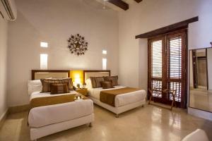 a bedroom with two beds and a couch and a chandelier at Casa Gastelbondo in Cartagena de Indias