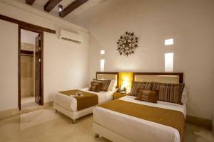 a hotel room with two beds and a chair at Casa Gastelbondo in Cartagena de Indias