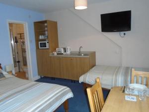 Habitación con 2 camas, mesa y TV. en The Florian en Weymouth