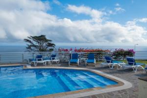 uma piscina com cadeiras e o oceano ao fundo em Apartments Madeira no Caniço