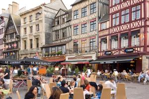 a group of people sitting at tables in a street with buildings at Novotel Suites Rouen Normandie in Rouen