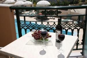 a table with two glasses of wine and grapes at Timos Hotel in Laganas