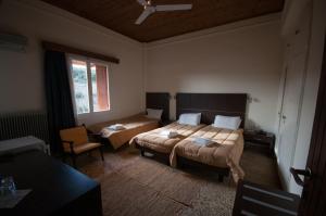 a hotel room with two beds and a chair at Avaton Hotel in Lygourio