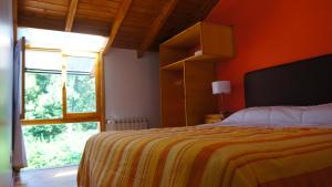 a bedroom with a bed with an orange wall and a window at ROSALES Alojamiento in Villa La Angostura