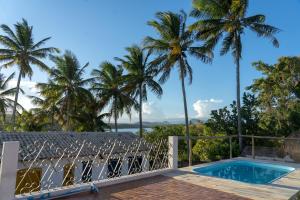 a balcony with a swimming pool and palm trees at Pousada Vila Sol Maior in Guarapari