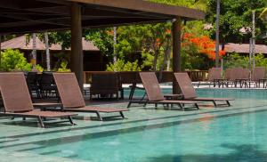 a group of chairs sitting next to a swimming pool at Kûara Hotel in Arraial d'Ajuda