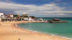 a beach with a group of people in the water at The Crown Bar & Guesthouse in Broadstairs