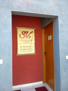 un muro rosso con un cartello sopra accanto a una porta di Acomodações Silvestre a Taubaté