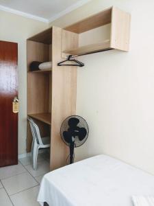 a room with a bed and a desk with a fan at Acomodações Silvestre in Taubaté