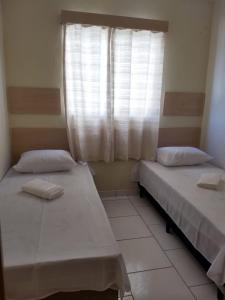 two beds in a room with a window at Acomodações Silvestre in Taubaté