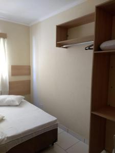 a small room with a bed and some shelves at Acomodações Silvestre in Taubaté