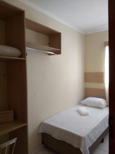 um pequeno quarto com uma cama e um closet em Acomodações Silvestre em Taubaté