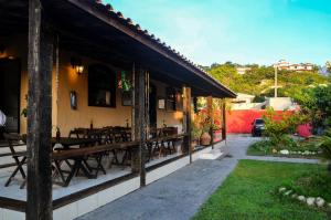 a restaurant with wooden tables on the side of a building at Pousada Bela Casa Geribá in Búzios