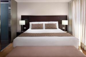ein großes Bett in einem Hotelzimmer mit zwei Lampen in der Unterkunft Exe Suites Reforma in Mexiko-Stadt