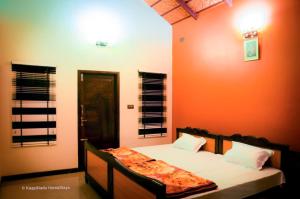 a bedroom with a bed with an orange wall at Butter Clouds HomeStay in Chikmagalūr