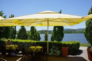 a man sitting at a table under a yellow umbrella at Hotel Haus am See in Olbersdorf