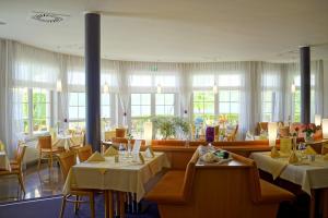 a restaurant with white tables and chairs and windows at Hotel Haus am See in Olbersdorf