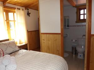 a bedroom with a bed and a bathroom with a toilet at Hostal Robinson in Puerto Puyuhuapi