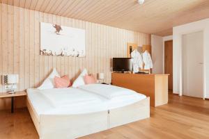 a bedroom with a large white bed and a television at Hotel Hubertus Mellau GmbH in Mellau