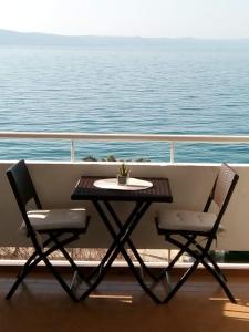 une table et deux chaises sur le balcon d'un navire dans l'établissement Apartments and Rooms Nikša, à Podgora