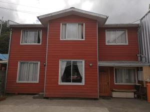 a red house with white windows at Hostal El mirador 2 in Castro