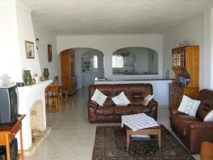 sala de estar con muebles de cuero marrón y cocina en Vila Bushiribana - Vivenda Johanna, en Lagos