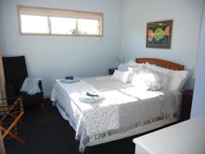 een slaapkamer met een wit bed en een raam bij The Orchard in Whakamarama