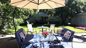un patio con mesa, sillas y sombrilla en Charles Street Vacation Home, en Lethbridge