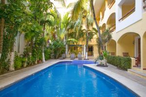 a swimming pool in a courtyard with palm trees at Hotel Riviera Caribe Maya in Playa del Carmen