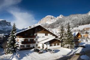 a ski lodge with two cars parked in the snow at B&B Residence Adria in Corvara in Badia