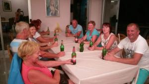 a group of people sitting around a table with beer bottles at Sobe Ivan-Popić in Međugorje