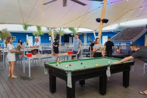 een groep mensen die rond een pooltafel staan bij Bounce Cairns in Cairns