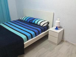 a bed with blue and white sheets and a night stand at Fuengirola Apartment in Fuengirola