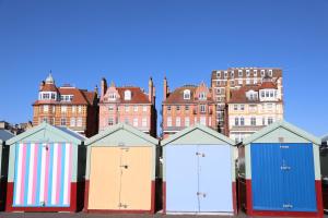 une rangée de cabanes de plage colorées en face des bâtiments dans l'établissement Olive Tree Apartment Hove, à Brighton et Hove