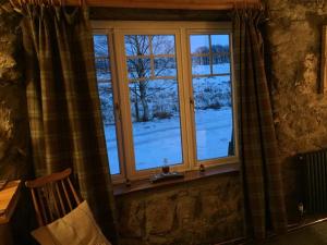 een raam met uitzicht op een met sneeuw bedekte tuin bij The Barn | Aberlour in Aberlour