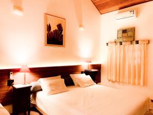 Parque Hotel Holambra في أولامبرا: غرفة نوم بسرير ذو شراشف بيضاء