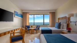 ein Hotelzimmer mit 2 Betten und einem Flachbild-TV in der Unterkunft Park Royal Beach Cancun - All Inclusive in Cancún
