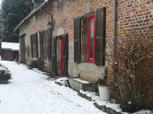 ein Backsteingebäude mit roten Fenstern und Schnee auf dem Boden in der Unterkunft L'écrin du Val de Sambre in Maubeuge