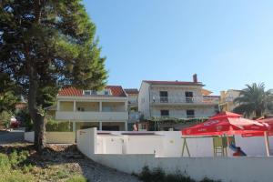 ein Haus mit einem roten Regenschirm und einem Gebäude in der Unterkunft Apartment Bela1 - close to the beach in Trogir