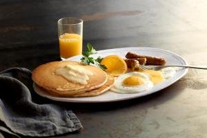 een bord pannenkoeken, eieren en spek met een glas sinaasappelsap bij Golden Nugget Lake Charles in Lake Charles