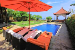 - un parasol rouge et des chaises à côté de la piscine dans l'établissement Ocean Beachfront Villa Dini, à Banjar