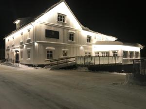 Un grand bâtiment blanc avec des lumières allumées la nuit dans l'établissement Hotell Gamla Staden, à Kalix