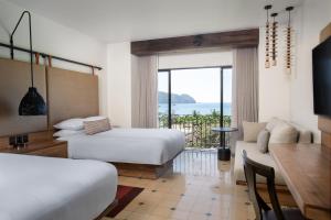 a hotel room with two beds and a table and a couch at Los Sueños Marriott Ocean & Golf Resort in Jacó