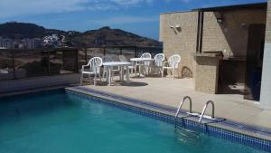 阿拉亞爾多卡博的住宿－APTO LINDO FRENTE PRAIA GRANDE，一个带桌椅的庭院和一个游泳池