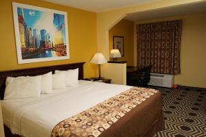 a hotel room with a large bed and a desk at Days Inn & Suites by Wyndham Harvey / Chicago Southland in Harvey