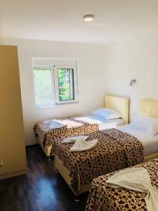 een kamer met 3 bedden en lakens met luipaardprint bij Delfini Holiday Homes in Ulcinj